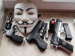 zdjęcie przedstawia trzy sztuki atrapy broni palnej i maskę na twarz z charakterystycznymi wąsami i brodą