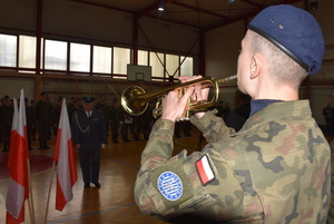 Uroczystość zakończenia szkoły klas maturalnych 1 Liceum Ogólnokształcącego im. 111 Eskadry Myśliwskiej PUL w Wołominie. Umundurowany uczeń gra na trąbce. Przed nim stoi umundurowany żołnierz w stanie spoczynku.