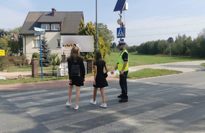 Policjant przeprowadza dzieci przez jezdnię